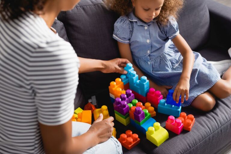 babysitter playing blocks with child on couch feature