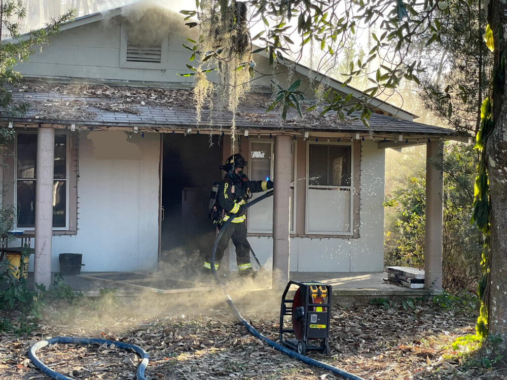 OFR house fire 12 27 22 firefighter standing with hose near open front door
