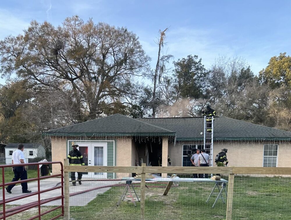 Marion County Fire Rescue NE Ocala home fire on February 20 2023 - firefighters outside home with smoke rising from roof
