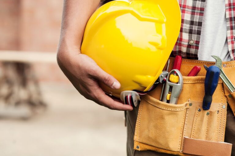 Construction worker holding hardhat with tools (stock image)