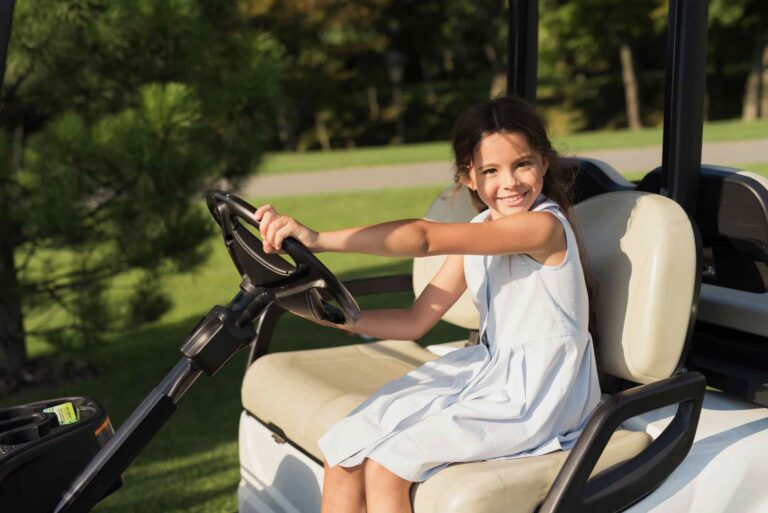 Child girl kid driving golf cart on golf course