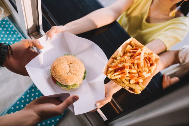 burgers and fries being handed to customer from food truck (stock image)