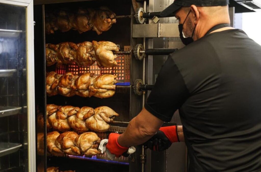 Employee cooking rotisserie chickens at Martin's BBQ