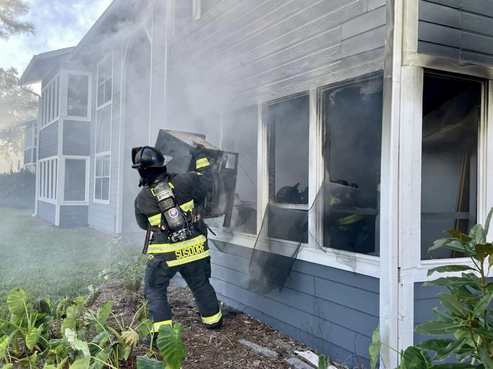 Ocala Fire REscue apartment fire on back porch (December 19, 2023) firefighter carrying freezer unit