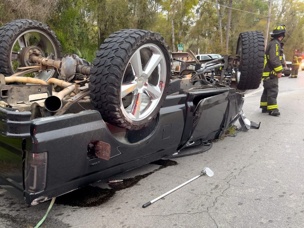 Two vehicle crash in northeast Ocala on March 5, 2024, sends three to hospital firefighters standing near overturned pickup truck (2) (photo by MCFR)