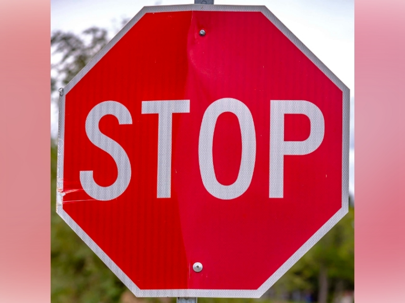 Red stop sign against trees and sky on a sunny day