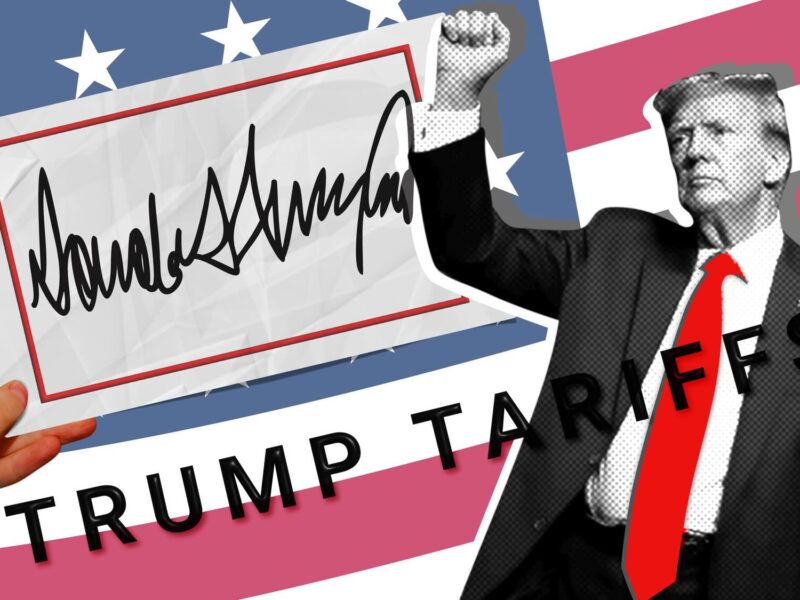 A hand holds a sign with Trump signature with Trump signature and the text Trump Tariffs against the backdrop of the American flag.