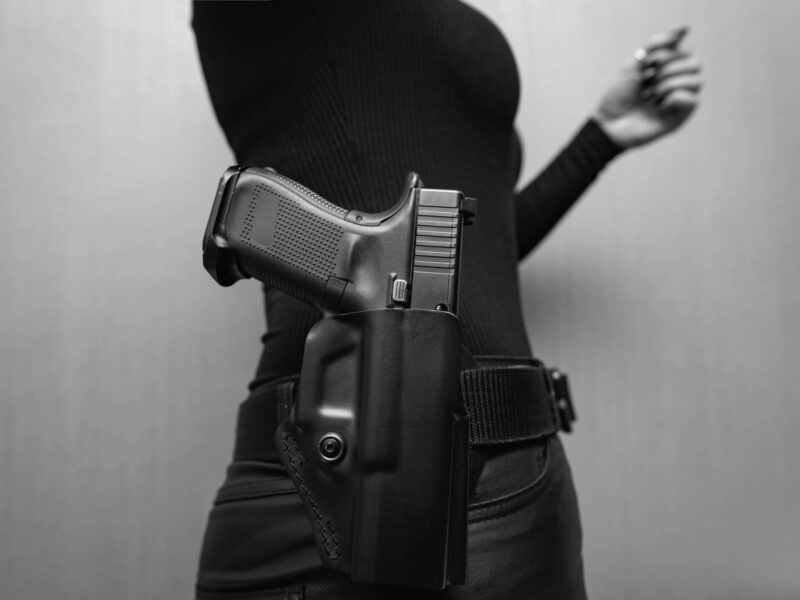 A pistol in a holster in a girl on a black jeans belt.