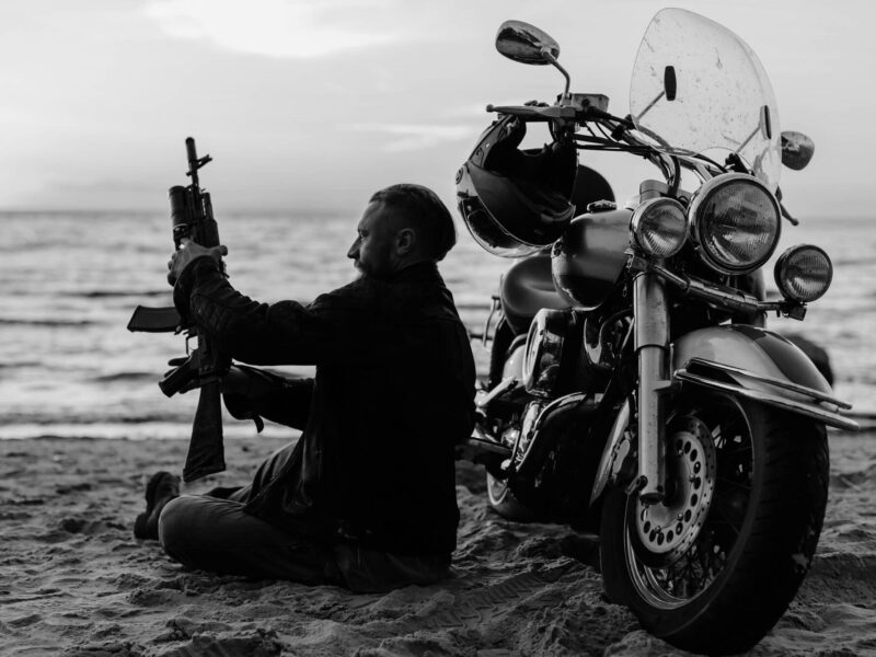 Biker/man with gun on beach in front of ocean
