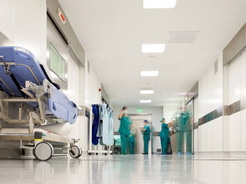 A medical facility or hospital hallway with doctors and a gurney