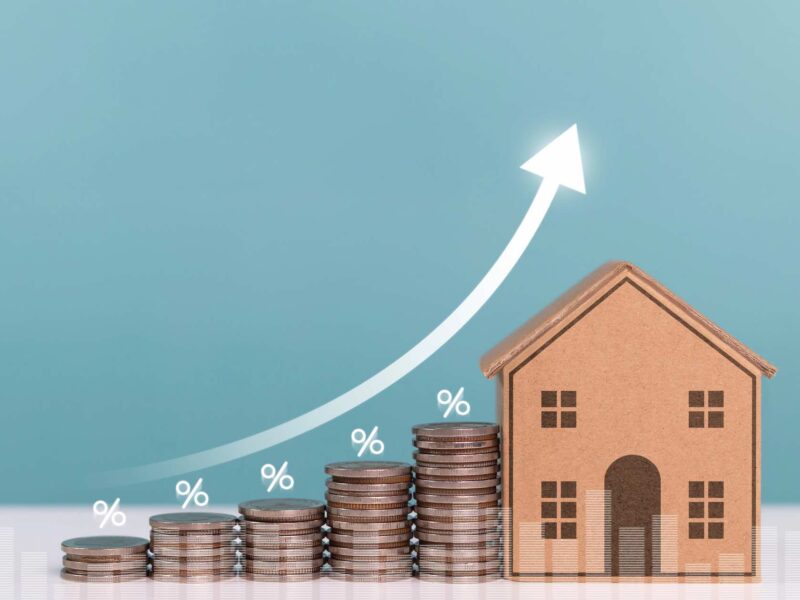 Stacks of coins next to a home demonstrating an increase in property taxes
