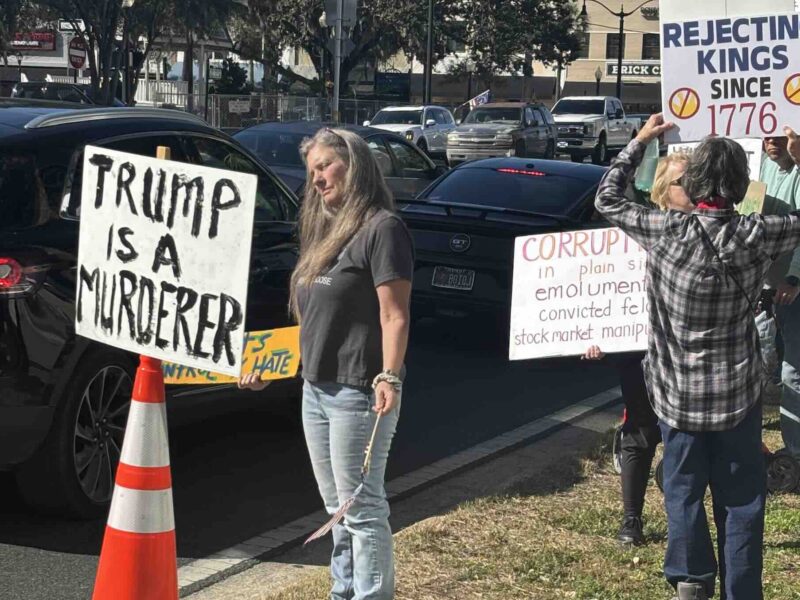 A protestor hold a "Trump is a Murderer" sign during the "No Kings" protest in downtown Ocala on January 17, 2026.