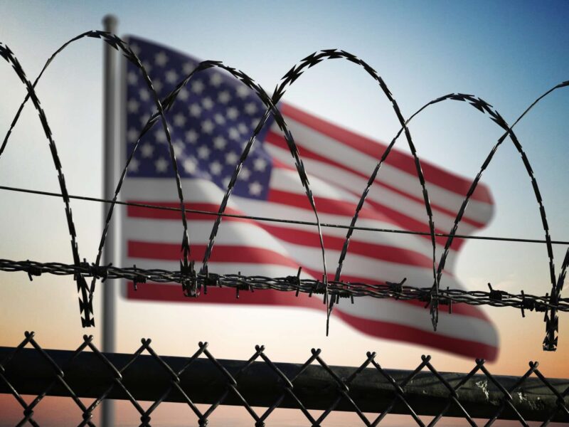 United States American Flag in front of barbed wire fence