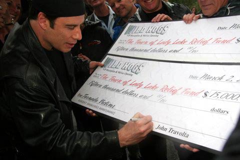 John Travolta signs a check for the Lady Lake tornado victims relief fund