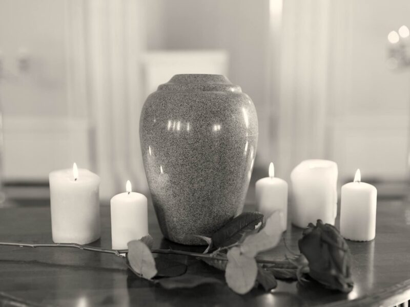 Cremation urn next to candles and flower