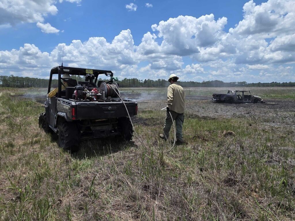 Crews extinguish a vehicle fire that started a wildfire in the Ocala National Forest