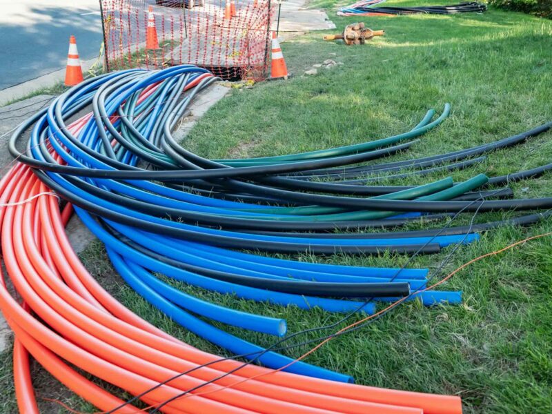 Wiring and conduits on the ground to illustrate fiber optic cable installation
